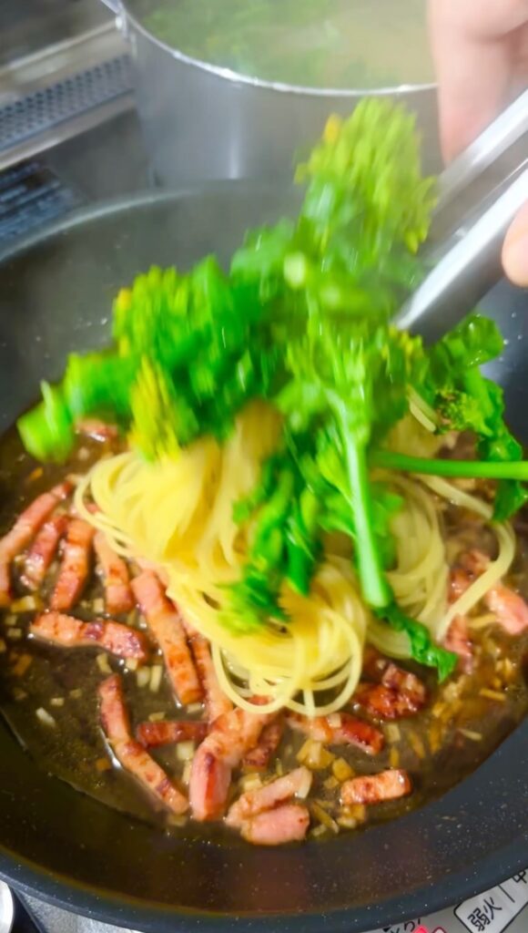 パスタを菜の花と一緒にソースに加える